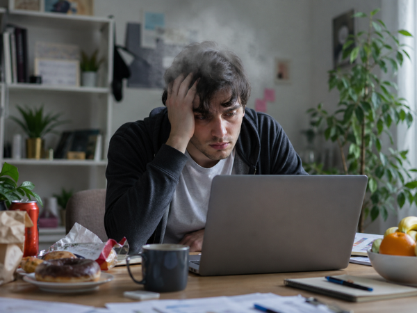 Person experiencing brain fog and lack of focus due to vitamin deficiency while working on a laptop